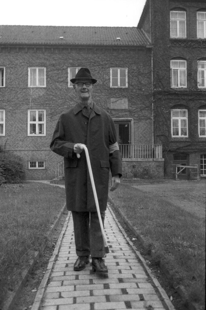 Blinder Mann mit Armbinde und Blindenstock. 